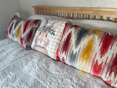 A bed with three decorative cushions including one with a rabbit design at The Coach House in Trelogan Hall Trelogan near Trelawnyd