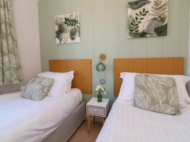 A bedroom with two single beds and a small table between them at Daffodil Lodge Mullacott near Ilfracombe