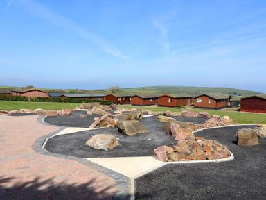 An outdoor area with lodges and rocks at Daffodil Lodge in Mullacott near Ilfracombe