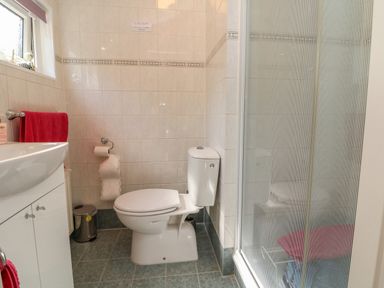 A bathroom with a toilet sink shower enclosure and red towels at Poppy Lodge in Mullacott Ilfracombe