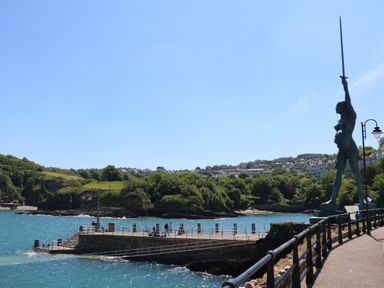 A seaside pier with people fishing and a large statue holding a sword at Poppy Lodge in Mullacott Ilfracombe