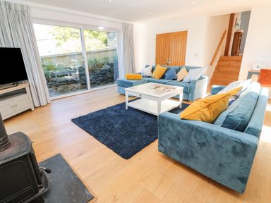 A living room with two blue sofas and a white coffee table on a dark rug at Chilowan in Trewarmett near Tintagel