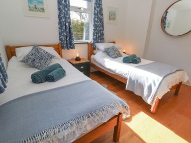 A bedroom with two single beds blue patterned cushions and rolled towels at Chilowan in Trewarmett near Tintagel