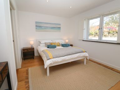 A bedroom with a white bed and bedside tables with lamps at Chilowan in Trewarmett near Tintagel