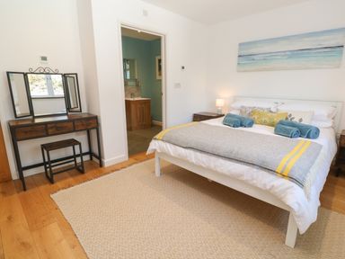A bedroom with a bed with rolled towels bedside tables and a dressing table at Chilowan in Trewarmett near Tintagel