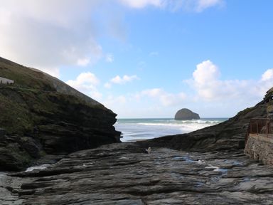 Rocky coastal area with a sea stack in the distance and a small animal on the rocks at Chilowan in Trewarmett near Tintagel