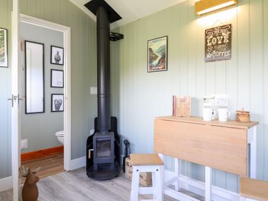 A room with a wood stove and a table with coffee cups at Cuckoo at Wild Valley Huts Llanrhaeadr-Ym-Mochnant