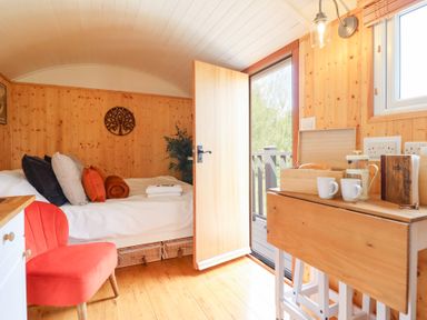 A bedroom with a bed and a table with mugs and bread at Red Kite at Wild Valley Huts Llanrhaeadr-Ym-Mochnant