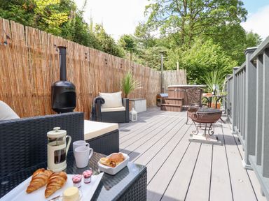 An outdoor deck with seating and a hot tub at Red Kite at Wild Valley Huts Llanrhaeadr-Ym-Mochnant