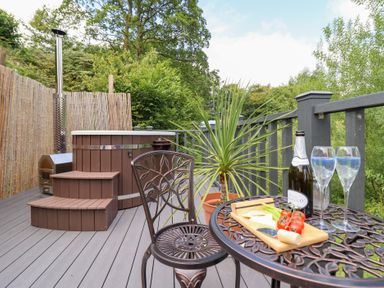 An outdoor seating area with a hot tub and table at Red Kite at Wild Valley Huts Llanrhaeadr-Ym-Mochnant