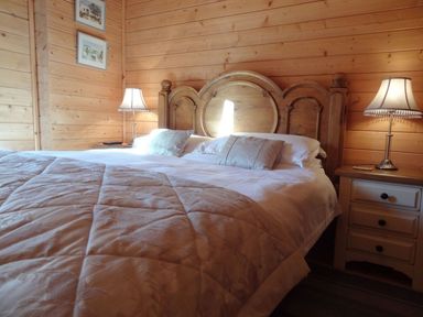 A bedroom with a wooden headboard bed two bedside tables and lamps at Valley Lodge Oakfordbridge near Bampton