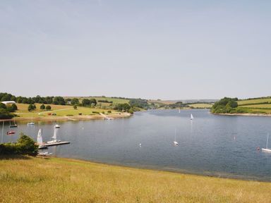 A river with sailboats and grassy banks surrounded by fields and trees at Valley Lodge Oakfordbridge near Bampton