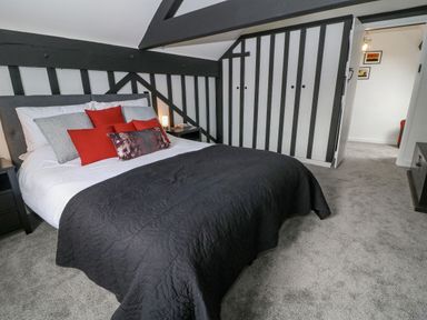 A bedroom with a bed featuring multiple pillows and a black quilt at Ellie's Cottage in Burford