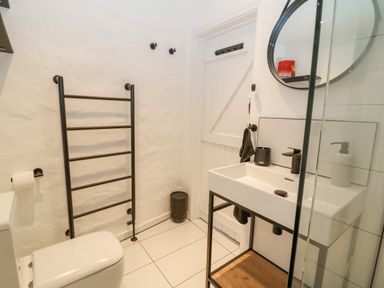 A bathroom with a toilet a towel rack a sink with a mirror and a white door at Ellie's Cottage in Burford