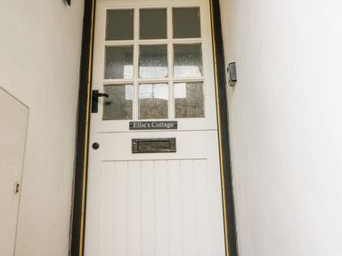 A white door with glass panels and a sign reading Ellie's Cottage Burford