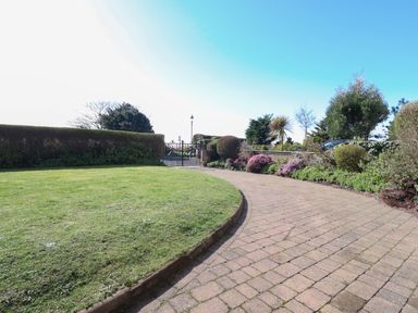 A garden with a paved curved pathway bordered by bushes and flowers at Ismay Dining Room Suite Titanic Interest in Waterloo Merseyside