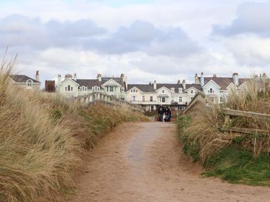 A sandy path bordered by grass and wooden railings leading to large houses in the background at Ismay Dining Room Suite Titanic Interest in Waterloo Merseyside