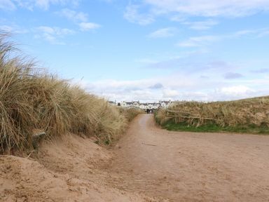 A sandy path between tall grass leading to white houses under a blue sky at Ismay Dining Room Suite - Titanic Interest in Waterloo Merseyside