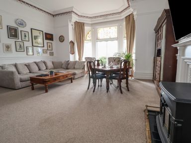 A living room with a beige sofa coffee table dining table chairs cabinet and a fireplace at Ismay Dining Room Suite - Titanic Interest Waterloo Merseyside
