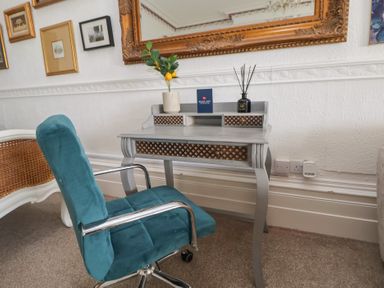 A small desk with a blue chair and framed pictures on the wall at Ismay Dining Room Suite - Titanic Interest in Waterloo Merseyside