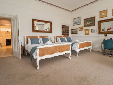 A bedroom with two beds with wicker headboards and footboards blue pillows and white bedding in Ismay Dining Room Suite Titanic Interest Waterloo Merseyside