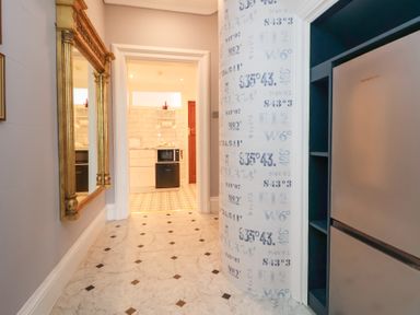 A hallway with a large mirror and patterned wallpaper showing a kitchen with appliances at Ismay Dining Room Suite Titanic Interest in Waterloo Merseyside