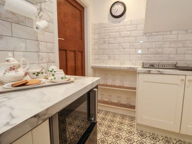 A kitchen with marble countertops white cabinets patterned floor and dishes on the counter at Ismay Dining Room Suite - Titanic Interest in Waterloo Merseyside