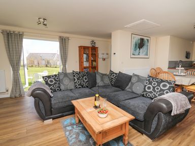 A living room with a large sectional sofa coffee table bookshelves and dining table at Brynteg Cottage in Tegryn