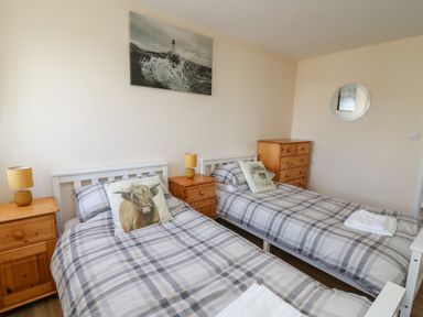 A bedroom with two single beds with animal print pillows and wooden furniture at Brynteg Cottage in Tegryn