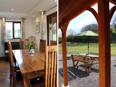 A dining room with a wooden table and chairs and a vase of tulips next to a covered outdoor seating area with a table and green umbrella at Riverside Lodge in Washford