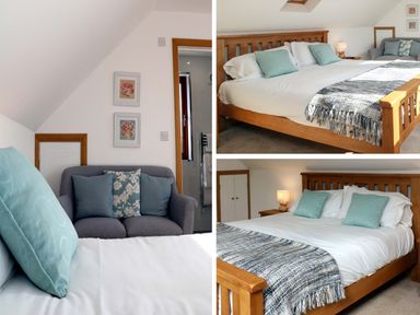 A bedroom with a wooden bed, pillows, a blanket, a grey sofa with cushions, wall art, and a bedside table with a lamp at Riverside Lodge in Washford