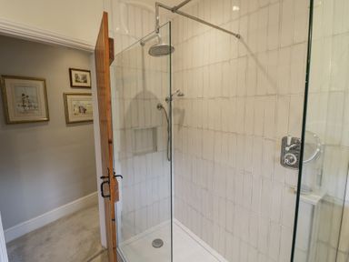 A bathroom with a glass shower enclosure and pictures on the wall at Lower Pack Horse Cottage in Winchcombe