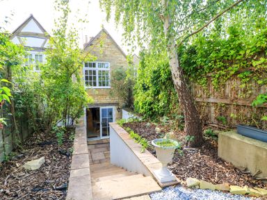 A garden with steps leading to an entrance at Lower Pack Horse Cottage in Winchcombe