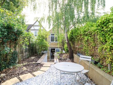 A garden with a table and chairs at Lower Pack Horse Cottage in Winchcombe