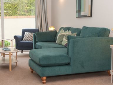 A sitting room with a teal sofa and armchair with cushions and a coffee table at Brooklands in Uplyme