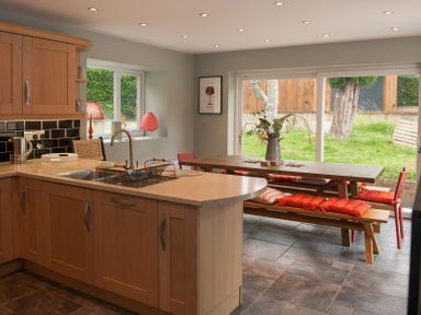 A kitchen with wooden cabinets and a dining area with a wooden table and bench seating at Brooklands in Uplyme