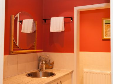 A bathroom sink with a round mirror and towels hanging on a rack at Brooklands in Uplyme
