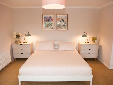 A bedroom with a bed and two nightstands each with a lamp and decor at Brooklands in Uplyme
