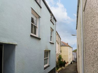 A narrow street with buildings on both sides under a partly cloudy sky at Winterbrook Cottage in Mevagissey
