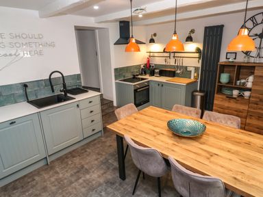 A kitchen with wooden dining table and chairs cabinets and appliances at Winterbrook Cottage in Mevagissey