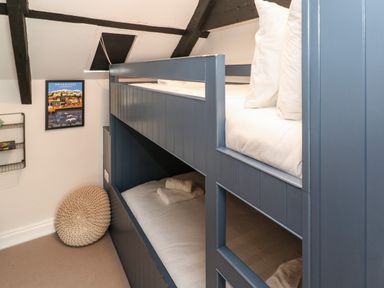 A bedroom with blue bunk beds and a knitted cushion on the floor at Winterbrook Cottage in Mevagissey