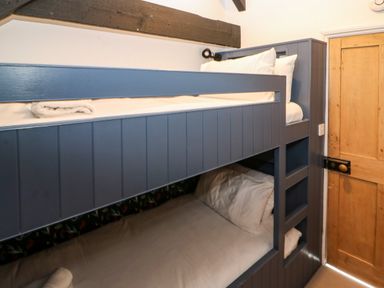 A bedroom with blue painted bunk beds and wooden door at Winterbrook Cottage in Mevagissey