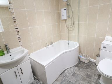 A bathroom with a bathtub shower combination sink with cabinet and toilet at Winterbrook Cottage in Mevagissey
