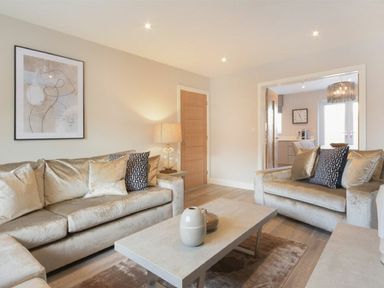 A living room with beige sofas a coffee table and a lamp at Sans Souci in Seahouses
