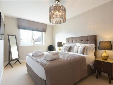 A bedroom with a double bed bedside tables a standing mirror and a window at Sans Souci in Seahouses