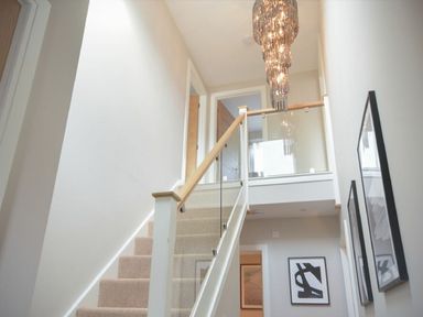 A stairway with glass and wood railing and hanging chandelier at Sans Souci in Seahouses