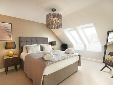 A bedroom with a large bed two bedside tables with lamps three skylight windows and a standing mirror at Sans Souci in Seahouses
