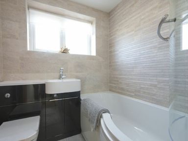 A bathroom with a bathtub a toilet and a sink under a window at Sans Souci in Seahouses