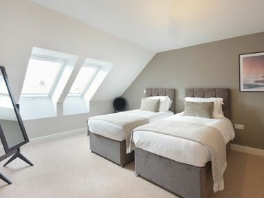 A bedroom with two single beds two skylight windows and a standing mirror at Sans Souci in Seahouses