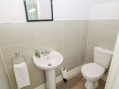 A bathroom with a pedestal sink toilet paper holder and toilet at Rose Lodge in High Newton-by-the-Sea near Embleton